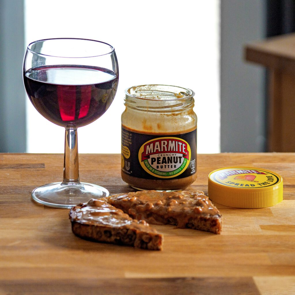 Банка Marmite с арахисовой пастой и бокал красного вина на столе
